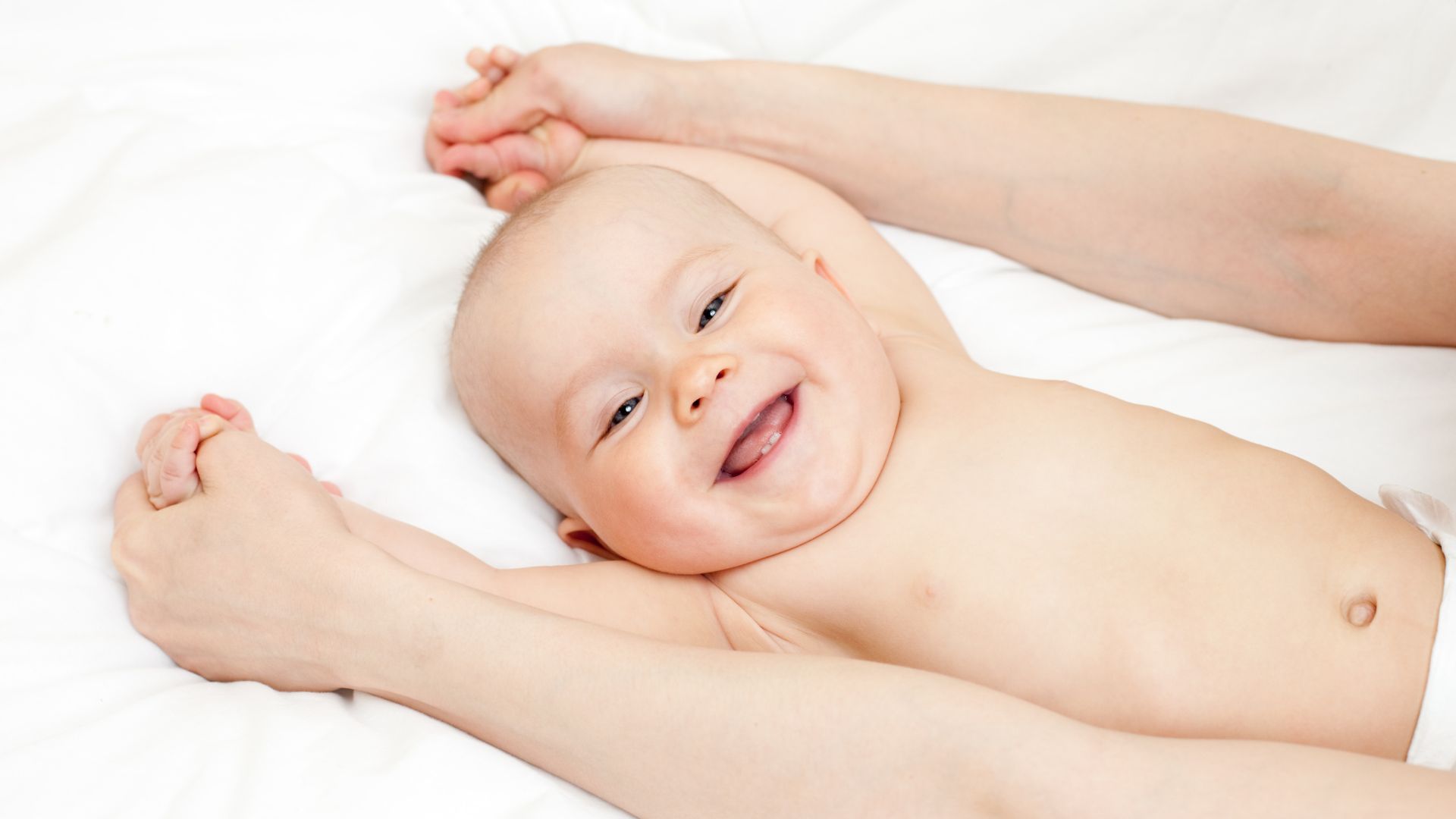 Smiling baby lying on white background, arms spread out