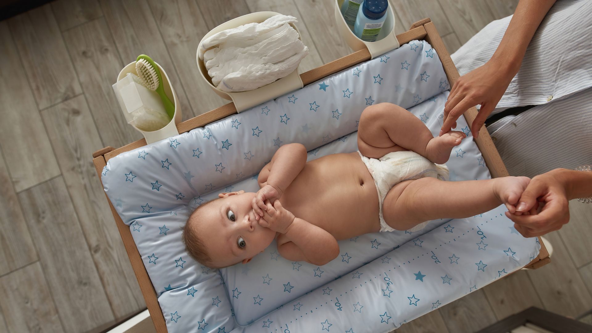 A baby in a diaper sitting on a bed