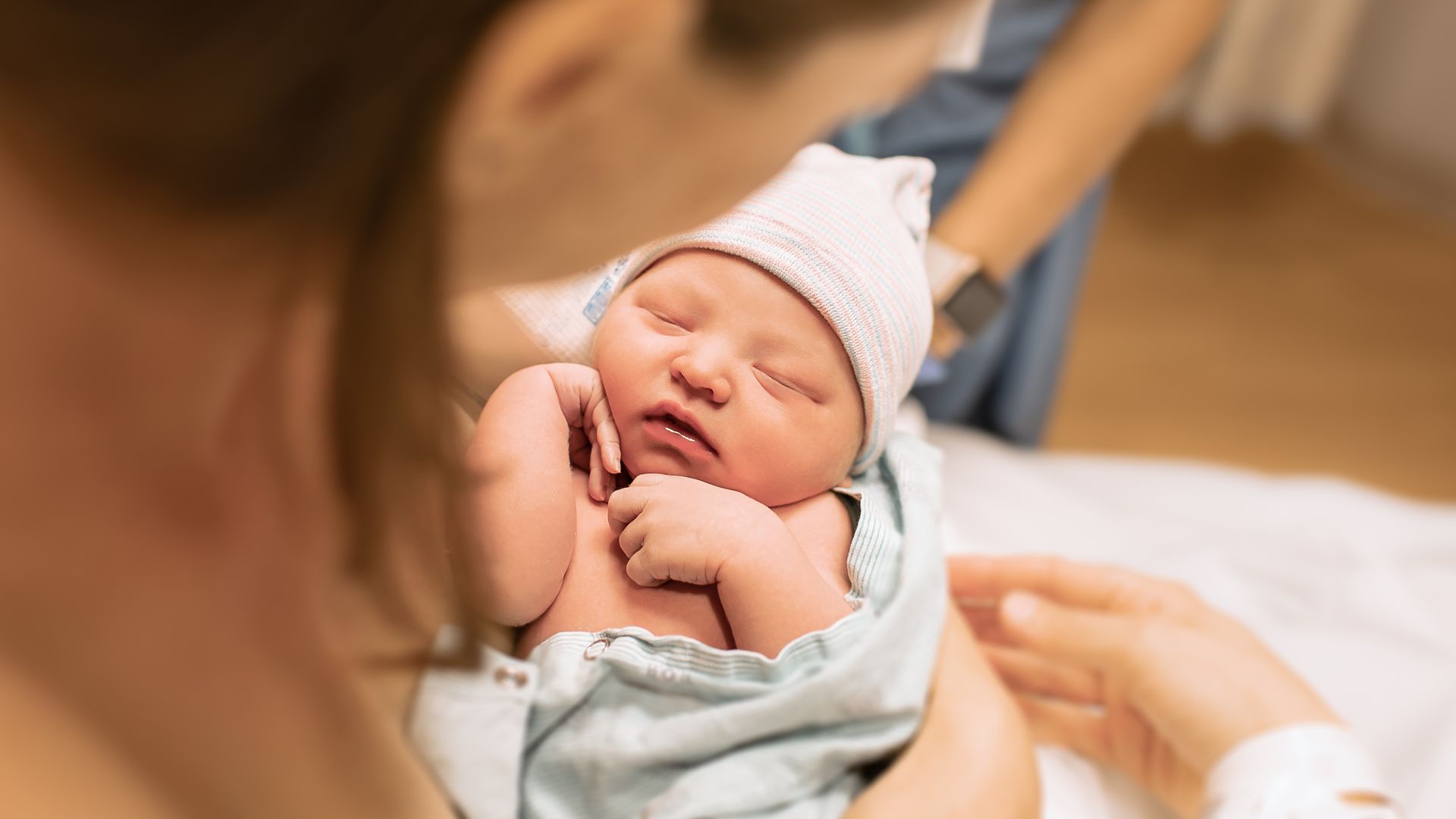 Newborn baby sleeping peacefully in soft blue outfit and striped hat