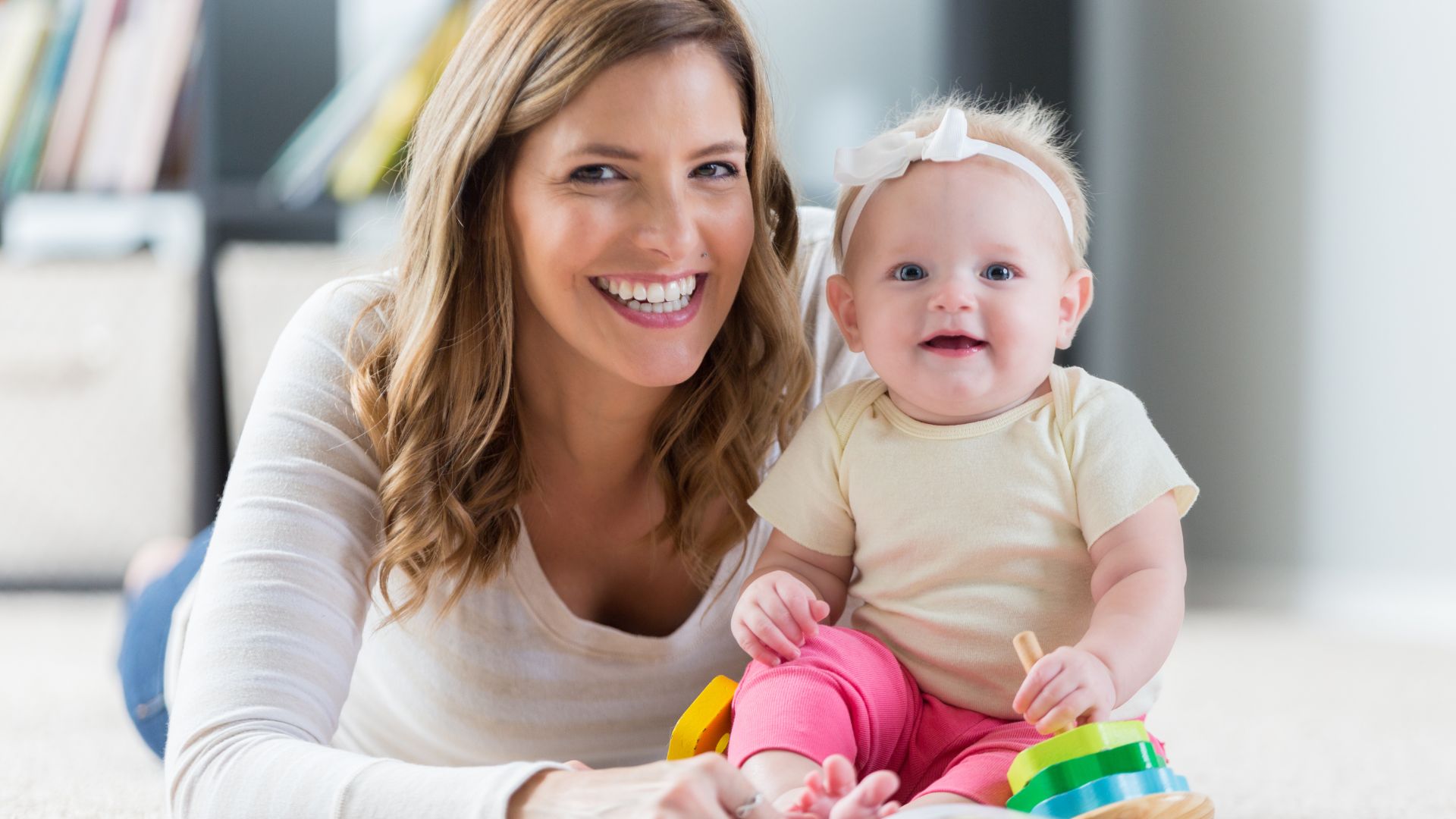 A woman holding a baby on the floor