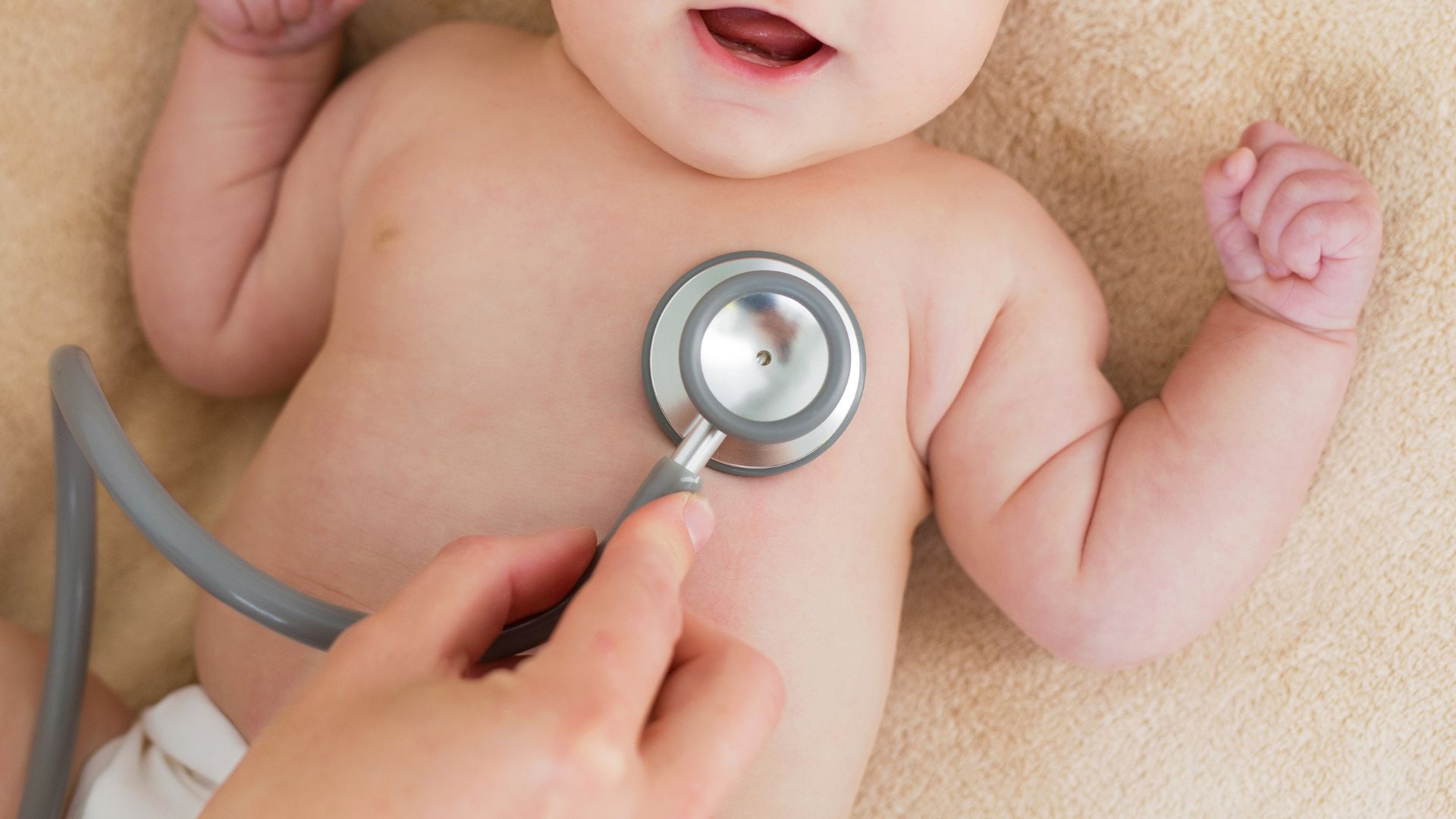 Doctor examining infant with stethoscope during routine pediatric checkup